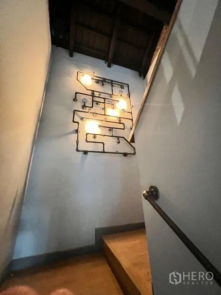 Retail Space for rent in Bangkok - Stairwell with decorative pipe-style wall lights and wooden steps.