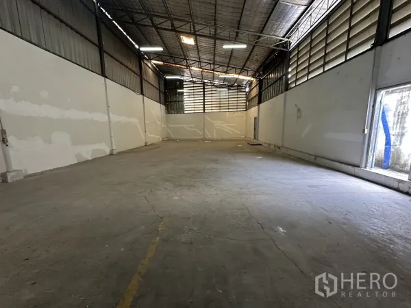Warehouse for rent in Suan Luang, Bangkok - High-ceiling warehouse hall with concrete floor and metal truss roof.