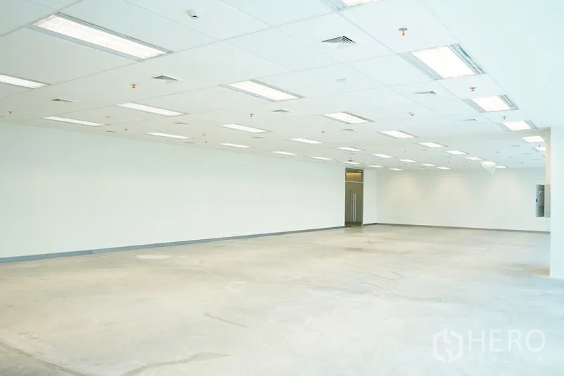Office Space for rent in Bang Na, Bangkok - Open workspace showing grid ceiling, nearby lift lobby access and polished concrete subfloor.