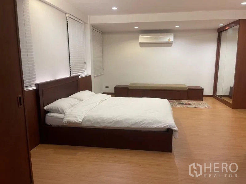 Townhouse for rent in Suan Luang, Bangkok - Large bedroom with wooden floors, built-in storage, bench seat and king-size bed.