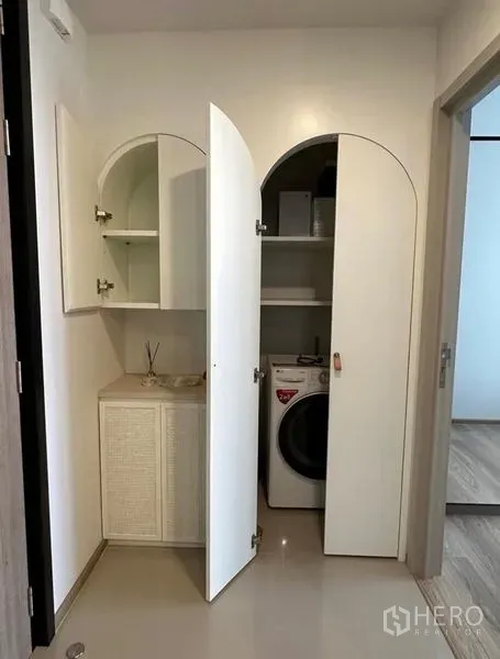 Condominium for rent - Open cabinets revealing shelves and a front-load washer in the condo.