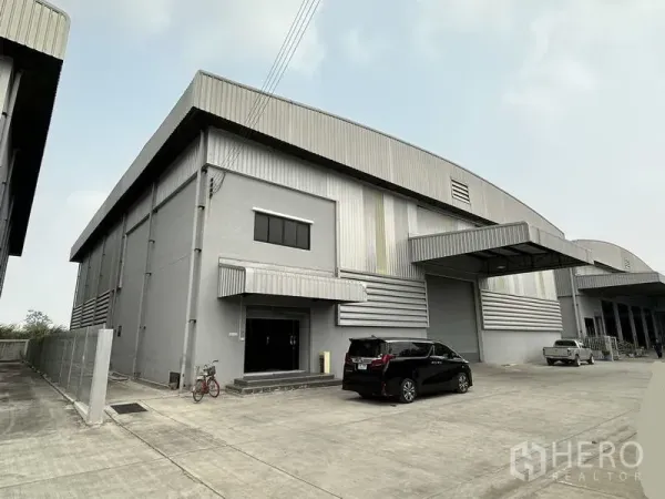 货栈 出租在Bang Phli, Samut Prakan - 灰色现代仓库外立面，金属墙面，带雨棚装卸区与宽阔混凝土院场，位于邦普里。