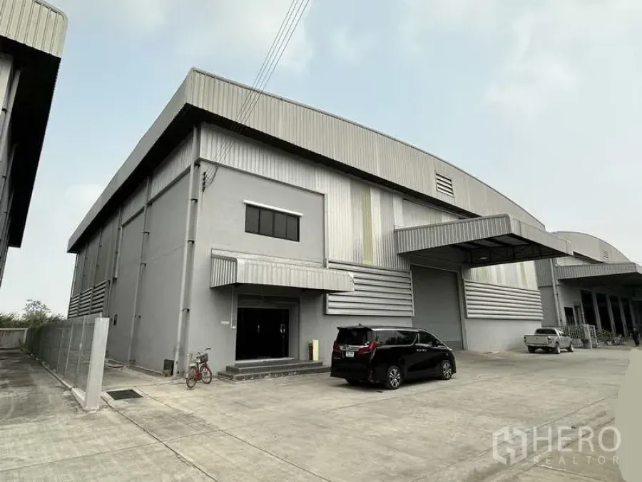 Warehouse for rent in Bang Phli, Samut Prakan - Modern grey warehouse exterior with metal cladding, loading bay canopies and a wide concrete yard in Bang Phli.