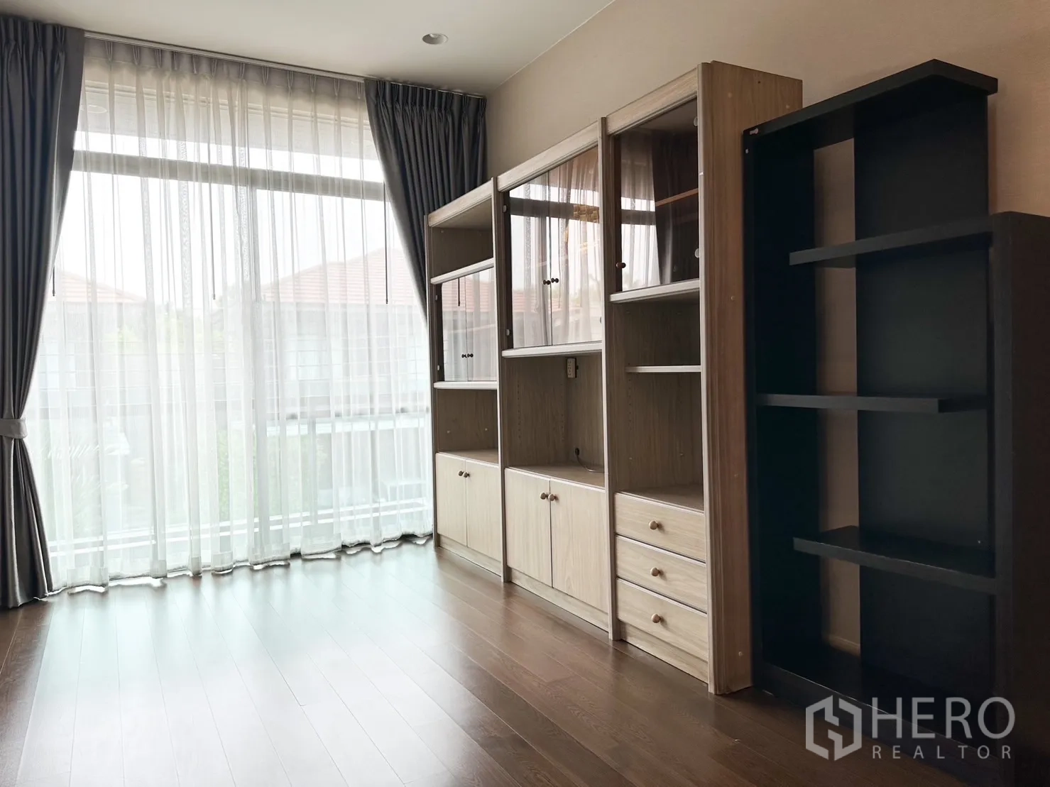 Detached House for rent or sale in Bang Kapi, Bangkok - Sunlit multipurpose room with display cabinets and full-height windows.
