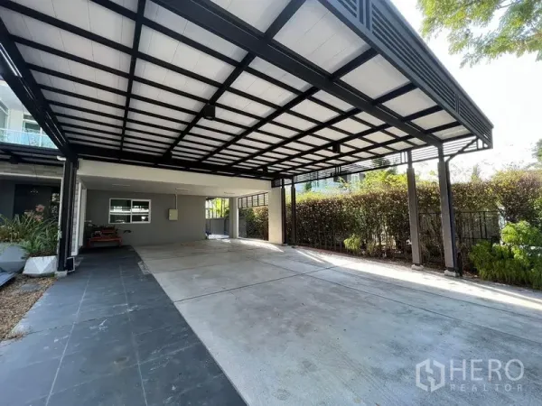 Detached House for sale - Oversized covered carport with steel roof and driveway bordered by hedges.