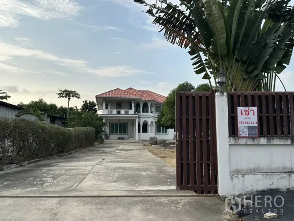 Home Office for rent - Gated entrance with long driveway leading to a two-storey white home office and large yard.