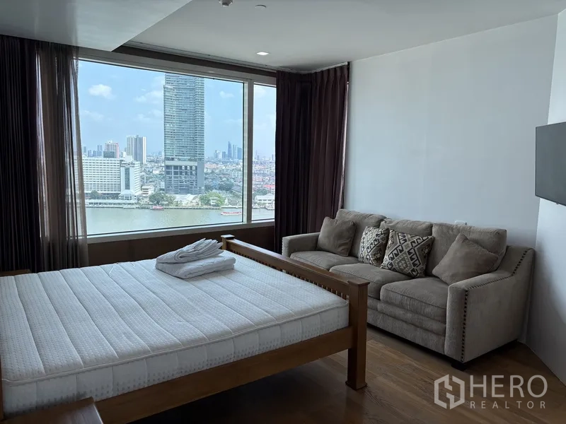 公寓 for rent in Khlong San, Bangkok - 卧室设大窗观河景，配木床与舒适沙发。