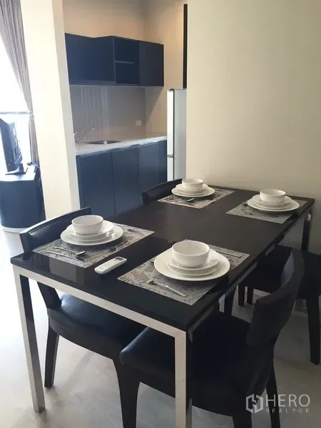 Condominium for rent in Khlong Toei, Bangkok - Dining area set for four beside the open kitchenette, creating a practical space for meals.