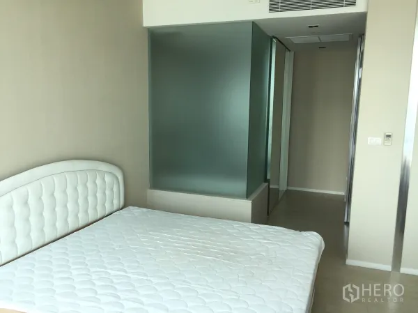 Condominium for rent in Watthana, Bangkok - Bright bedroom with white tufted headboard and a frosted glass partition to the wardrobe and bath.