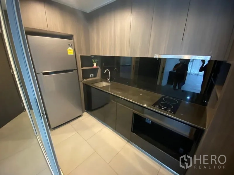 办公空间 出租在Phaya Thai, Bangkok - 茶水间配黑色台面、电磁炉与不锈钢双门冰箱。