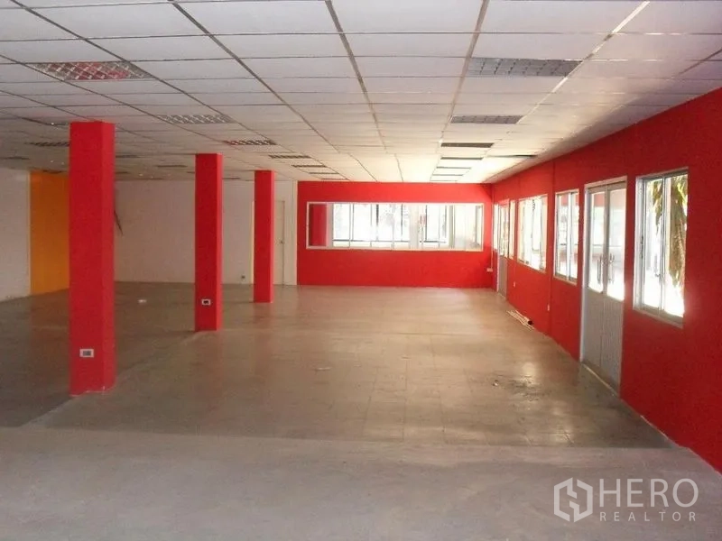 Retail Space for rent in Khlong Toei, Bangkok - Spacious open-plan retail interior with red columns, tiled floor, drop ceiling and large windows.