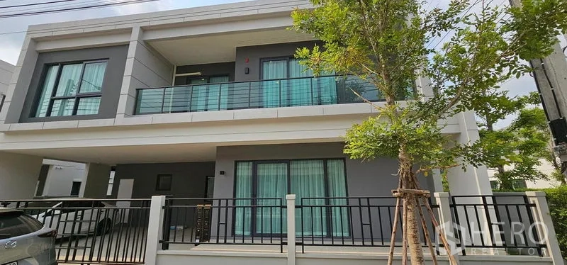Detached House for rent in Bang Phli, Samut Prakan - Modern two-storey detached house facade with balcony, glass railing and covered carport.