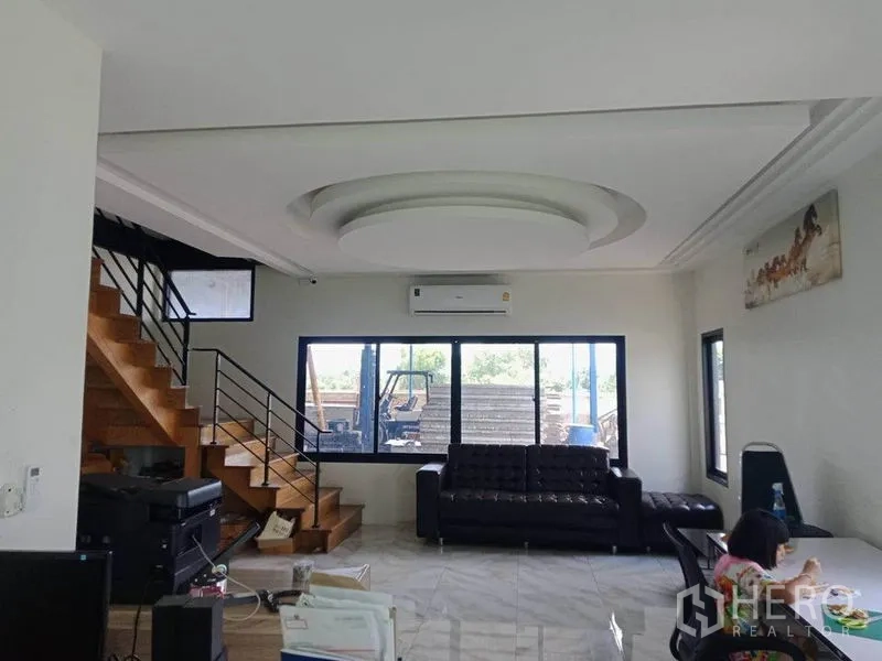 Warehouse for sale in Lam Luk Ka, Pathum Thani - Office lounge with staircase, large window, air conditioning and a black leather sofa.
