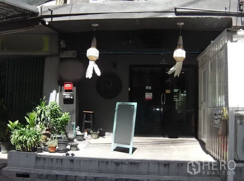 店屋 出租在Watthana, Bangkok - 临街店屋外观，玻璃门、悬挂灯饰、绿植与落地告示牌，靠近BTS Phra Khanong。
