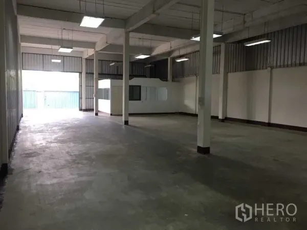 Warehouse for rent in Bueng Kum, Bangkok - Spacious warehouse hall with high ceiling, support columns and fluorescent lights, open concrete floor.