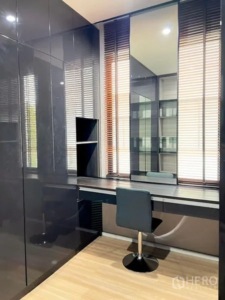 Townhouse for rent in Saphan Sung, Bangkok - Home office corner with glossy built-in wardrobes, long desk, large mirror and window blinds.