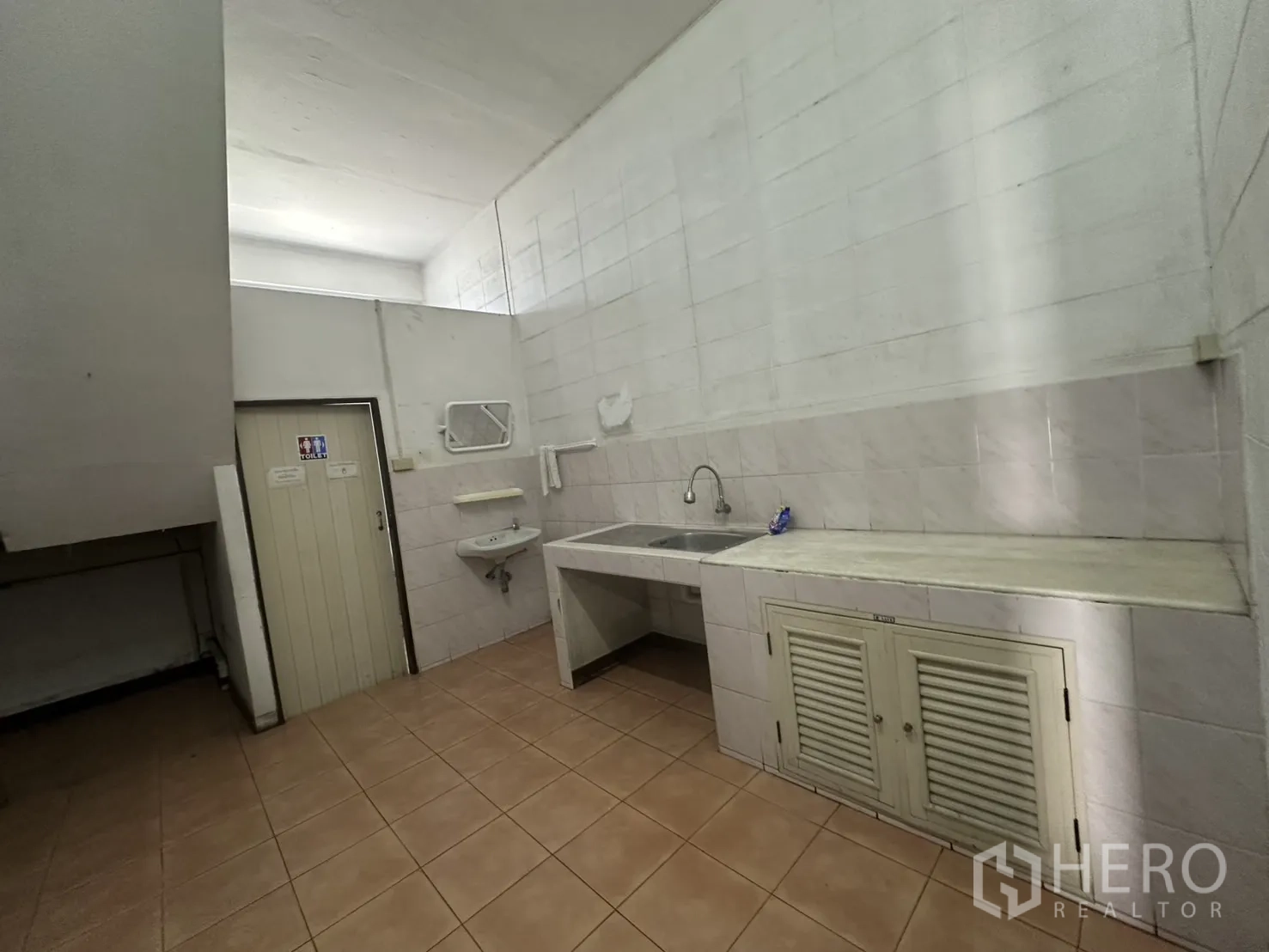Warehouse for rent in Bang Na, Bangkok - Pantry and wash area with sink, counter and restroom door.