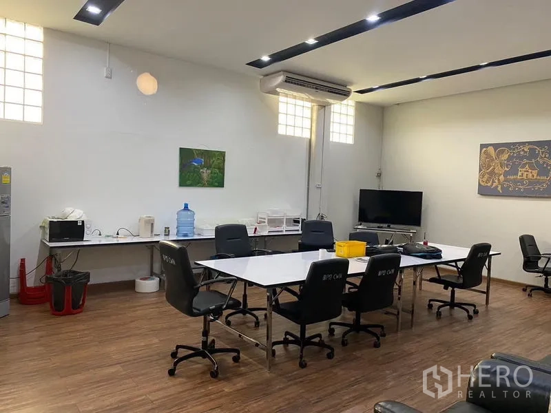 Warehouse for rent in Mueang Samut Prakan, Samut Prakan - Air-conditioned office and meeting room with desks, chairs and wood flooring inside the warehouse.