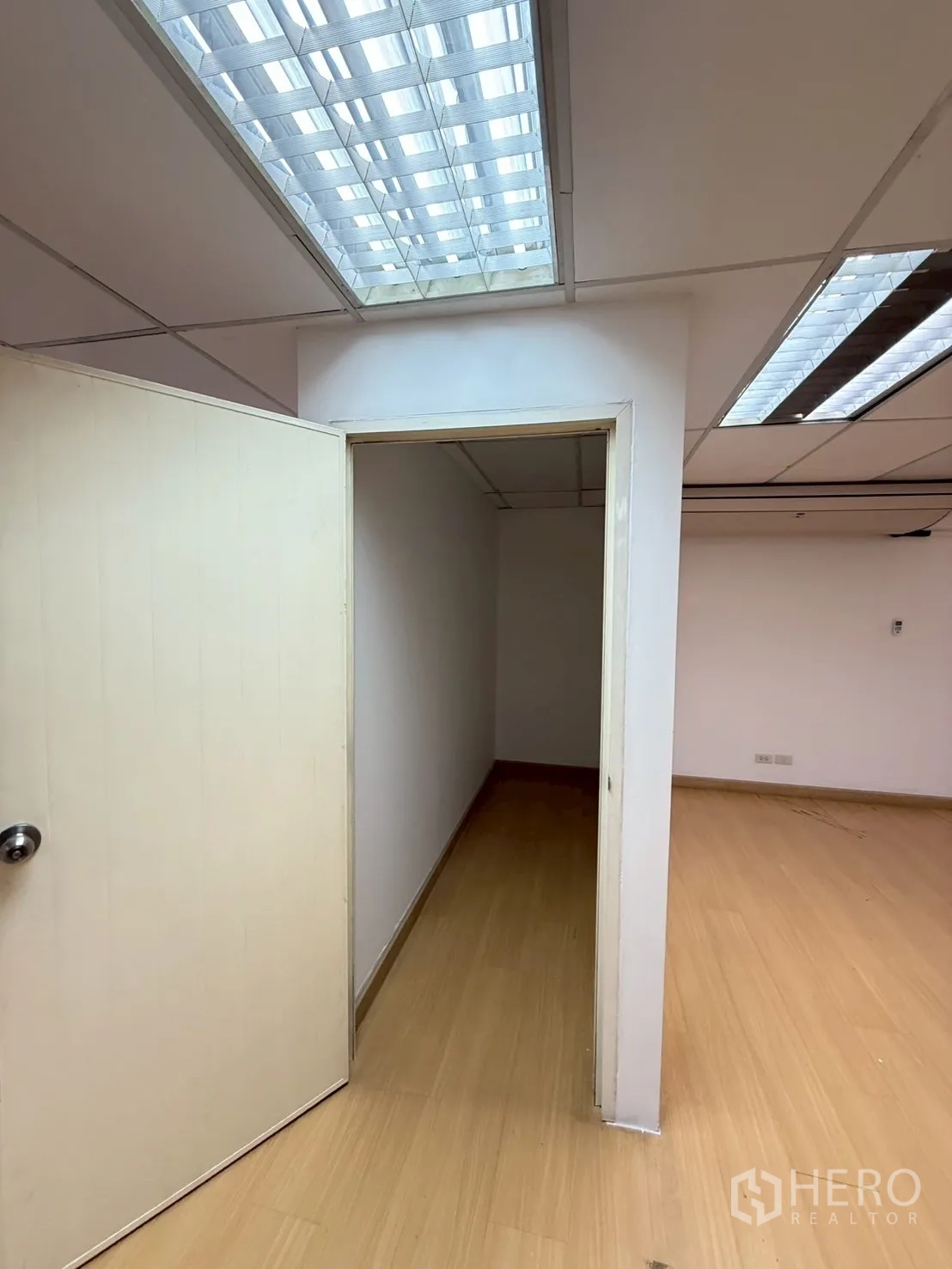 Office Space for rent in Watthana, Bangkok - Small private room or storage area with an open door, grid ceiling lights and laminate flooring.