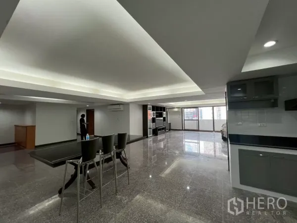 公寓 出租在Watthana, Bangkok - 超大客餐厅一体空间，托盘天花、光亮石材地面与落地窗。