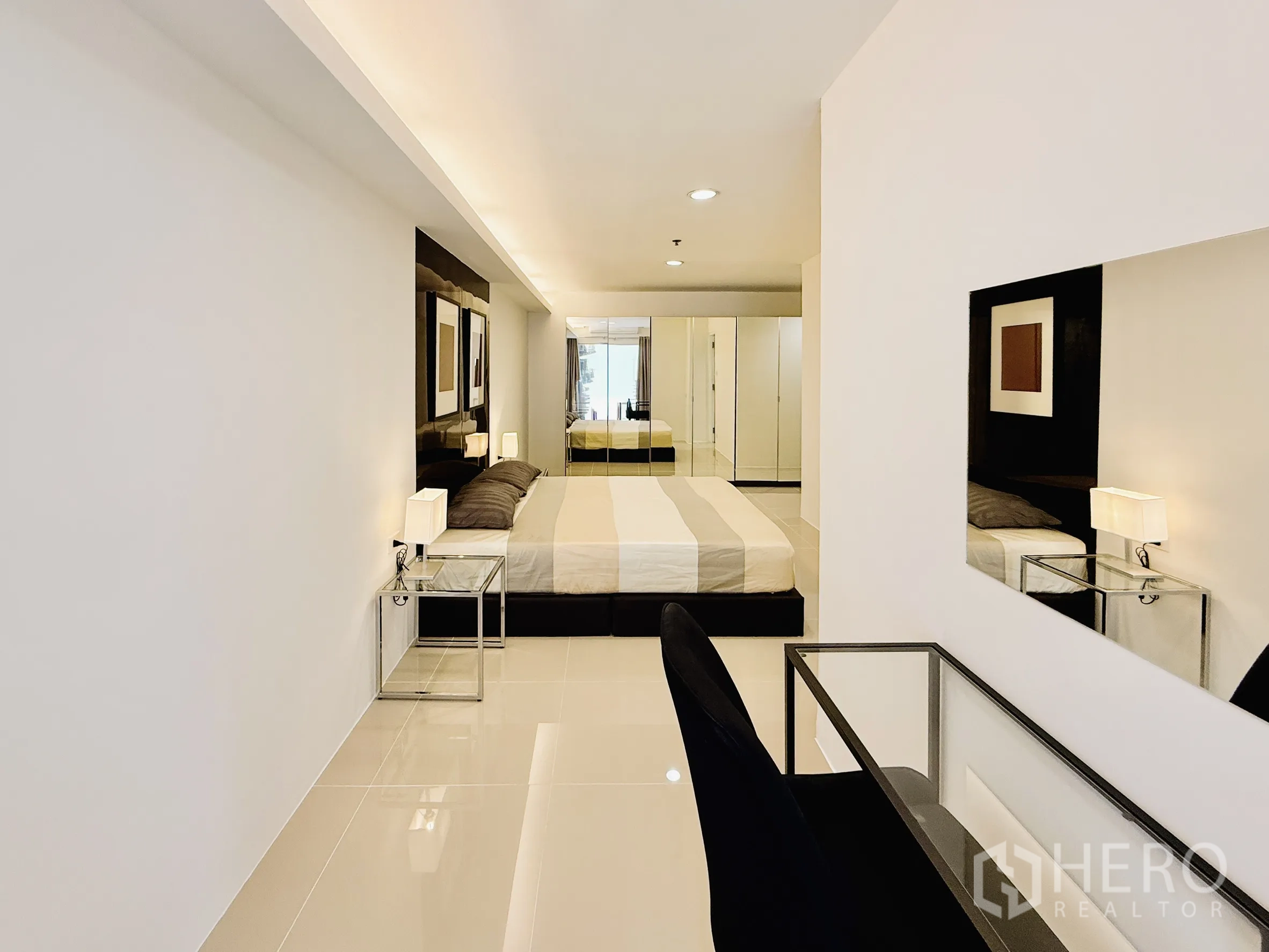 公寓 出租在Khlong Toei, Bangkok - 卧室带书桌角、白色墙面和装饰性床头板。