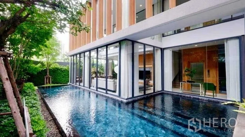 独立式住宅 出售在Huai Khwang, Bangkok - L形私人泳池环抱玻璃客厅，推拉门直通户外。