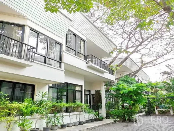 Detached House for rent in Khlong Toei, Bangkok - Contemporary house exterior with large windows, balconies and greenery