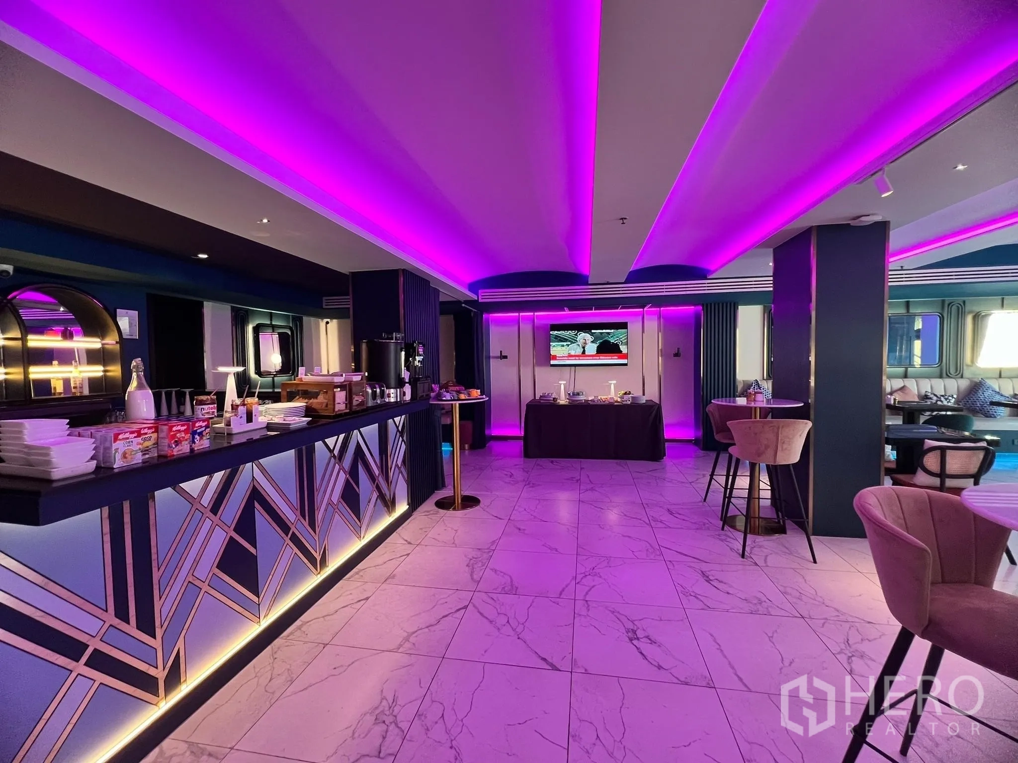 Retail Space for rent - Wide view of art-deco style bar counter with underlighting and buffet setup in a purple LED lit retail space.