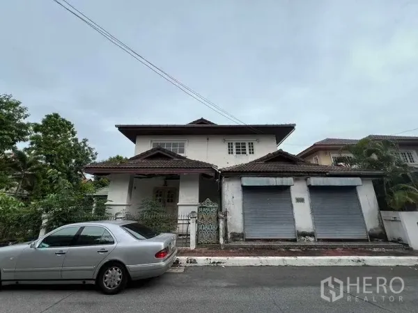 独立式住宅 出售在Phra Khanong, Bangkok - 正面远景，带院门与卷帘门的独栋住宅，坐落于安静街道。