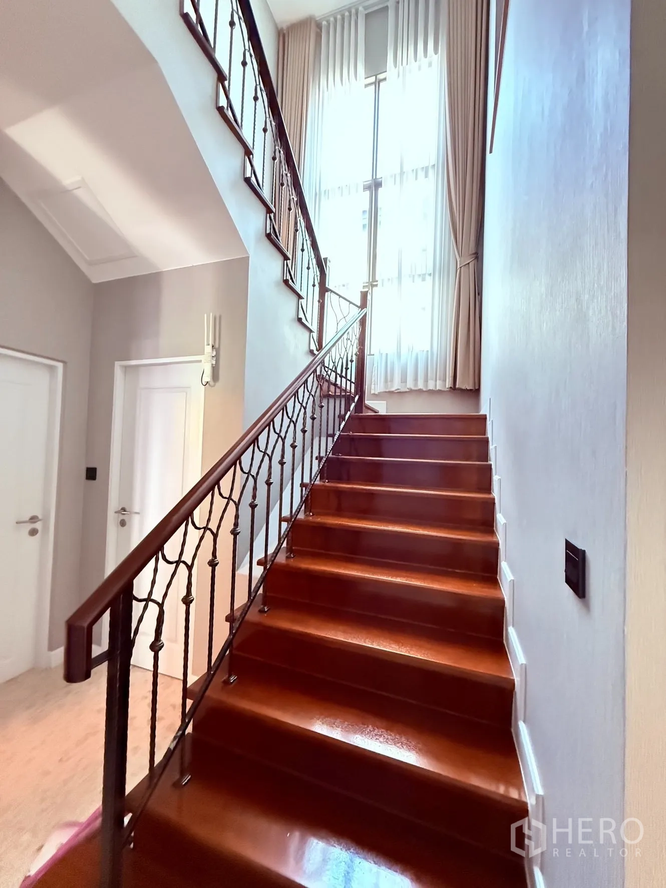 Detached House for rent or sale in Prawet, Bangkok - Staircase with wooden steps, wrought-iron railing, and a tall window bringing in light.