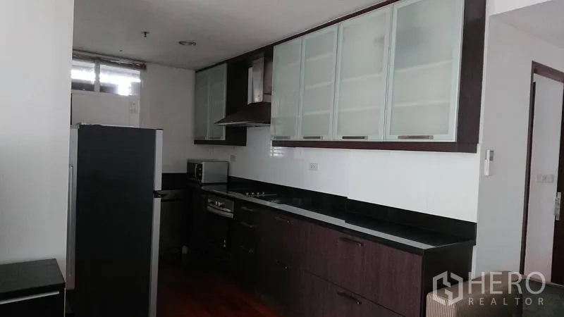 公寓 出租在Pathum Wan, Bangkok - 厨房另一角度：长台面、灶台与烟机、玻璃柜以及大冰箱。