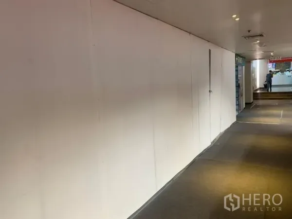 零售空间 出租 - 长条白色店面墙面对铺有地毯的走道