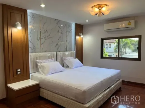 Detached House for rent in Samut Prakan - Air‑conditioned master bedroom with marble accent headboard and wood trims.
