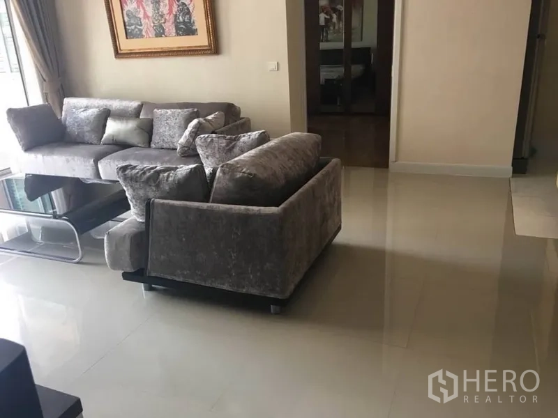 公寓 出租在Bang Rak, Bangkok - 开放式客厅，转角沙发、亮面地砖与落地窗。