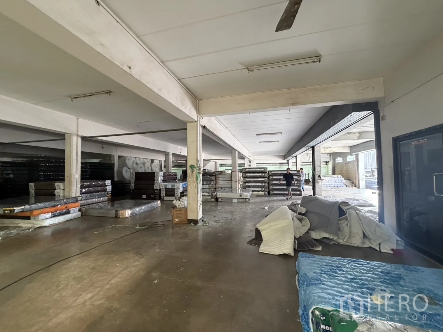 工厂 for rent or sale in Bang Bon, Bangkok - 仓储区，卷帘门开启，产品成堆摆放。