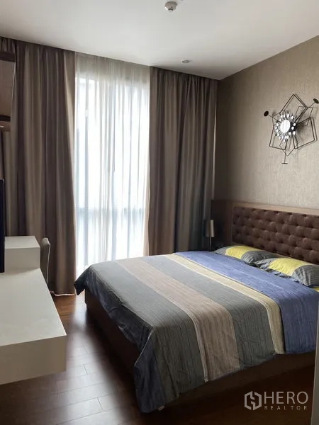 Condominium for rent in Watthana, Bangkok - Bedroom with upholstered headboard, large bed, floor‑to‑ceiling window and blackout drapes.
