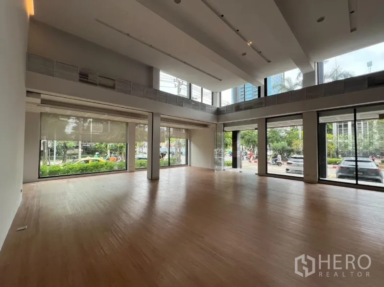 Retail Space for rent in Khlong Toei, Bangkok - Double-height showroom with floor-to-ceiling windows and wood floors.