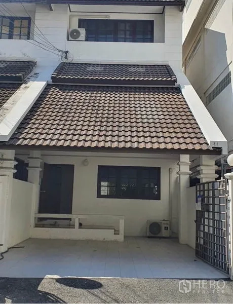 联排别墅 出租在Watthana, Bangkok - 两层联排别墅外观，坡屋顶与带门车棚。