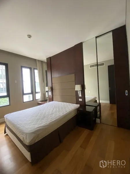 公寓 出租在Watthana, Bangkok - 明亮卧室，双人床、软包床头、木地板与镜面衣柜。