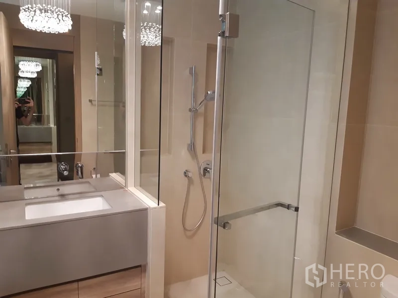 公寓 出租或出售在Watthana, Bangkok - 现代卫浴，玻璃干湿分离淋浴间、台盆柜与镜前灯，旁有浴缸。