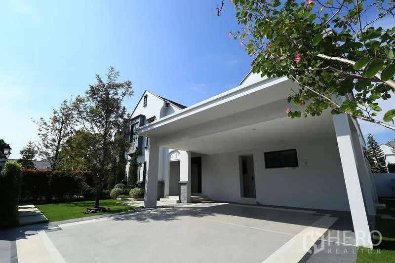 Detached House for rent in Saphan Sung, Bangkok - Covered carport with wide driveway next to a manicured yard.