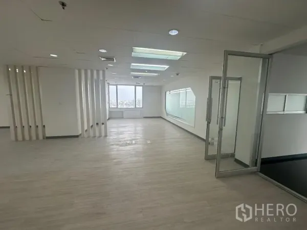 Office Space for rent - Bright open-plan office with light wood floors, recessed lighting, and a glass door leading to a meeting room with city views.