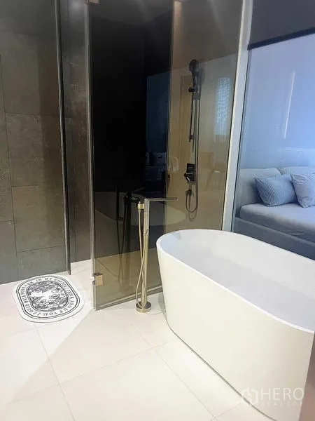 Condominium for rent in Khlong Toei, Bangkok - Modern bathroom with freestanding soaking tub and glass-enclosed rain shower.