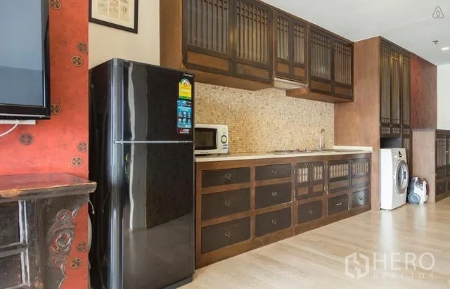 Condominium for rent in Khlong Toei, Bangkok - Full kitchen with dark wood cabinetry, mosaic backsplash, refrigerator and washing machine.
