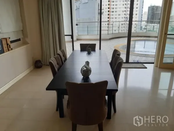 Condominium for rent in Khlong Toei, Bangkok - Dining room with six-seat table opening to a spacious terrace with skyline views and a round water feature.