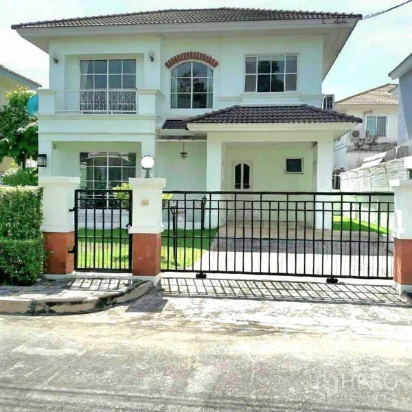 独立式住宅 出租在Prawet, Bangkok - 房屋正立面，黑色滑动大门与有顶车道。