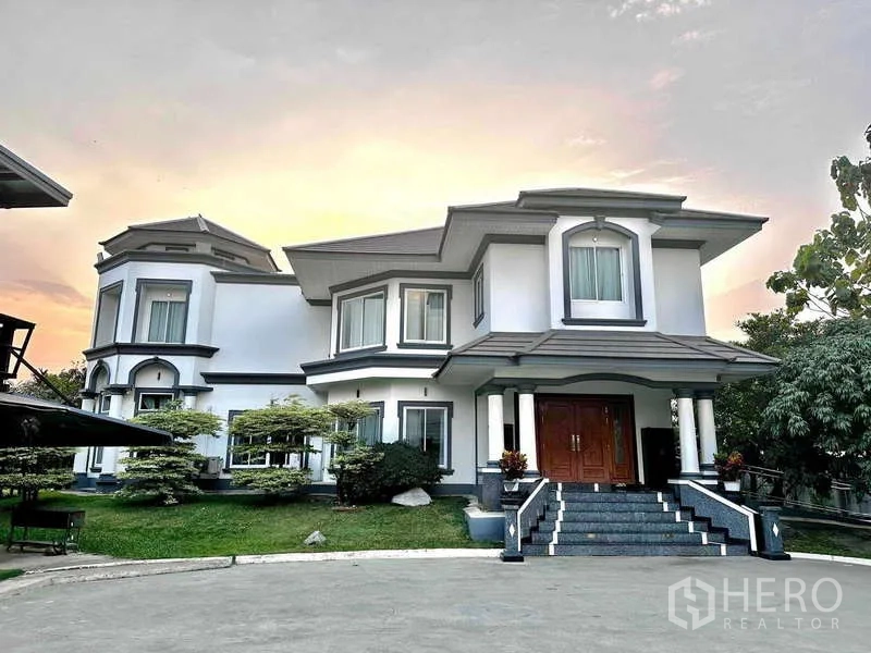 Detached House for sale in Khlong Luang, Pathum Thani - Grand entrance of the detached house with double doors, porch columns and landscaped lawn.