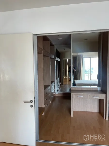 Condominium for rent in Khlong Luang, Pathum Thani - Dressing area with mirrored sliding wardrobe, built-in drawers, and a vanity overlooking the bedroom.