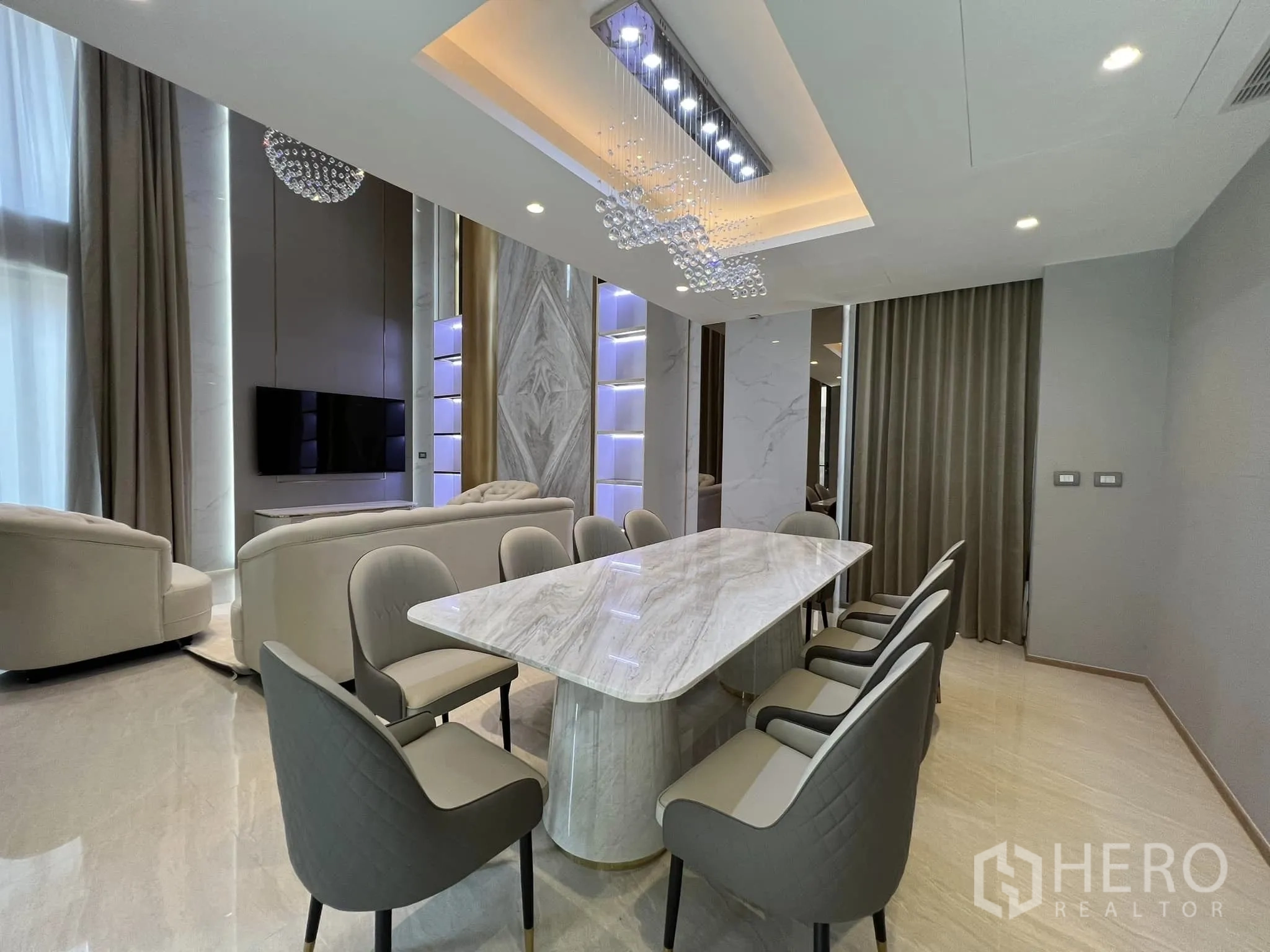 Detached House for rent or sale in Yan Nawa, Bangkok - Open-plan dining space facing the lounge and TV wall with tall curtains.