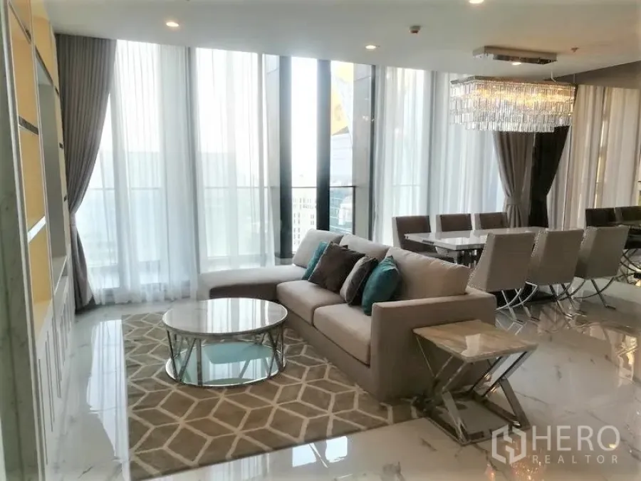 公寓 出租在Pathum Wan, Bangkok - 采光充足的客厅，L型沙发、地毯、圆形茶几与餐区吊灯